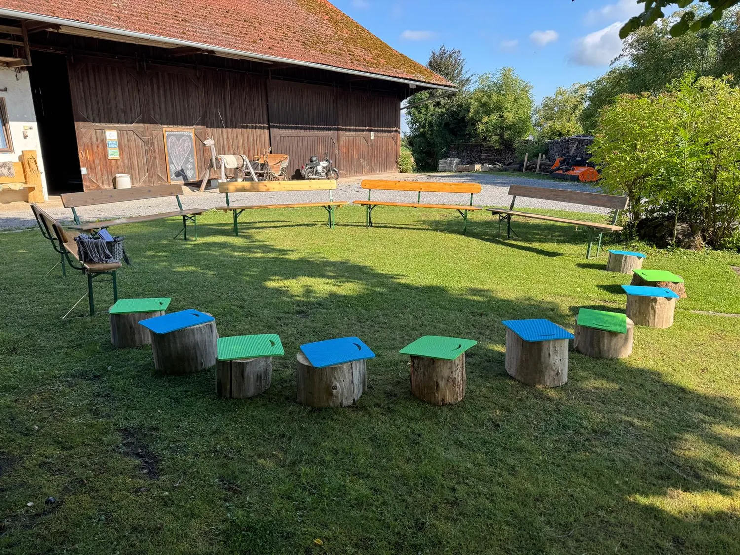 Stanglhof Sengkofen - Bauernhof - Dieser rustikale Sitzbereich im Freien verfügt über einen Kreis aus Holzhockern und Bänken, die für ein gemütliches Beisammensein arrangiert sind
